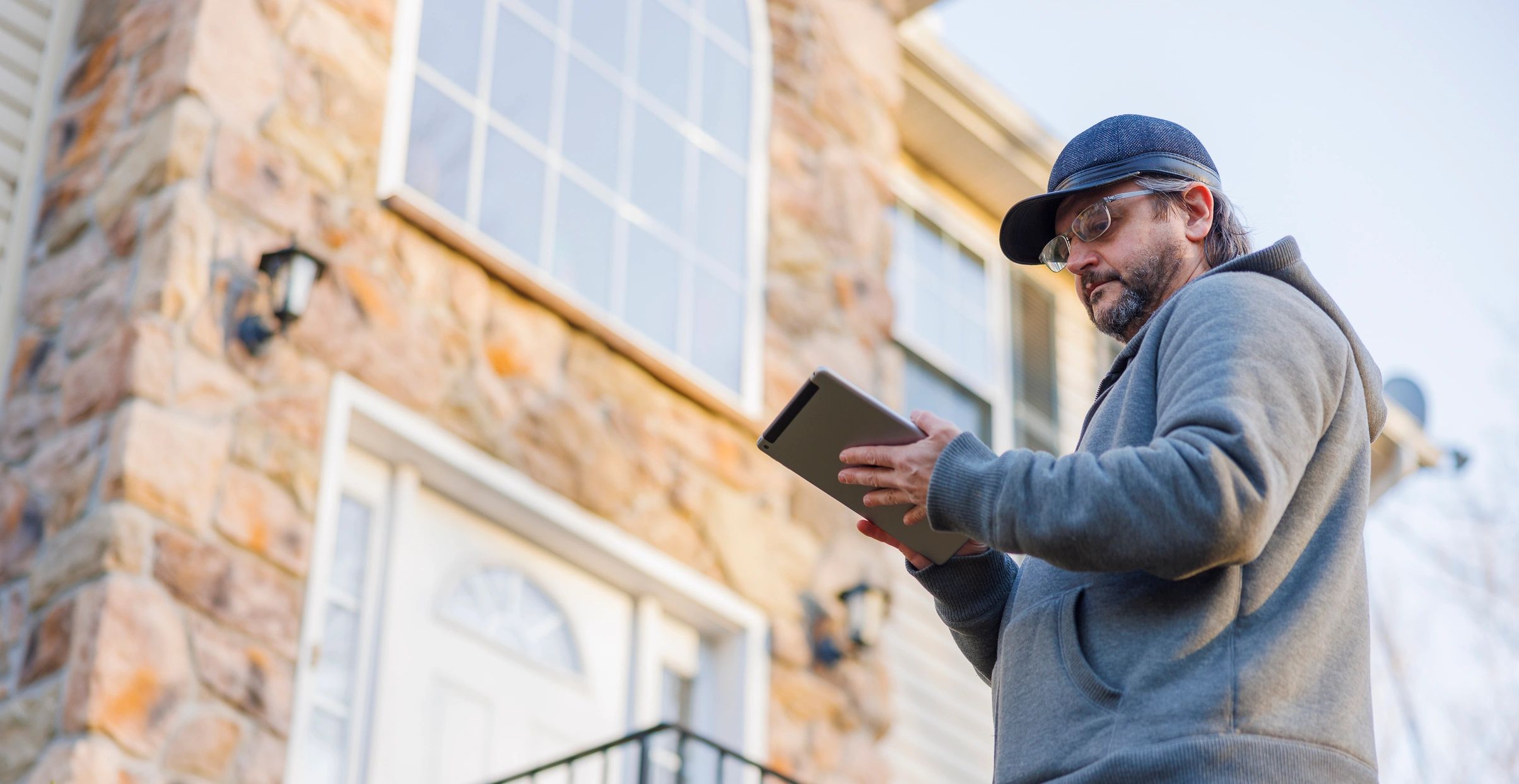Inspector using a tablet while inspecting a townhouse exterior